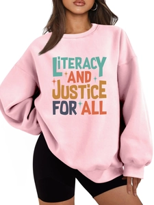 Detail of light pink sweatshirt featuring literacy and justice colorful art text print