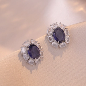 Macro di orecchini con zircone viola ovale e contorno di pietre su velluto