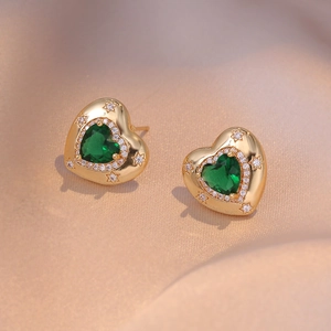 Detail of vintage heart earrings with green zircon and gold star embossing on silk