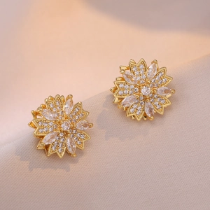 Elegant gold flower stud earrings with sparkling cubic zirconia on beige silk background