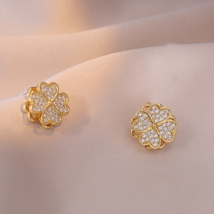 Orecchini a quadrifoglio con zirconi bianchi su sfondo di seta color champagne elegante