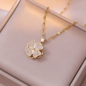 Dettaglio di una collana a quadrifoglio dorata con zirconi in una scatola da regalo