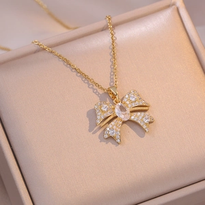 Elegant gold bow necklace with white zircon pendant on champagne jewelry box