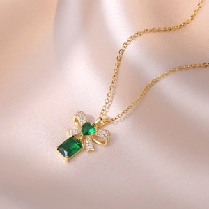 Titanium steel necklace featuring a golden bow pendant with green heart-shaped zircon stones