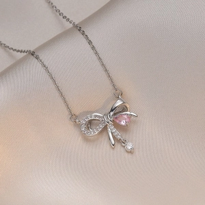 Elegant silver bow necklace featuring a pink teardrop stone and zircon on silk fabric