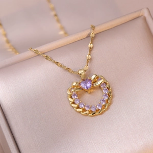 Vue macro d'un pendentif cœur doré avec gemmes violettes sur velours champagne