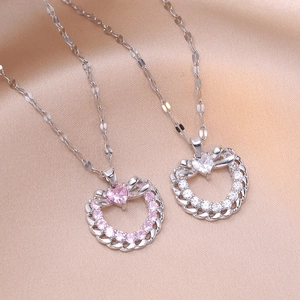 Détail de pendentifs cœur avec gemmes roses et blanches et nœuds sur satin