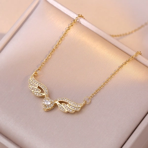 Golden heart angel wing necklace with sparkling zircon accents on champagne satin cushion