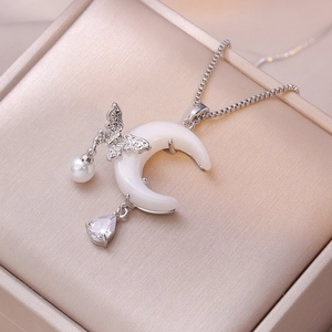 Collier élégant en argent avec pendentif lune, perles et papillon sur un support en soie