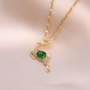 Golden emerald reindeer necklace with crystal accents on pink satin background
