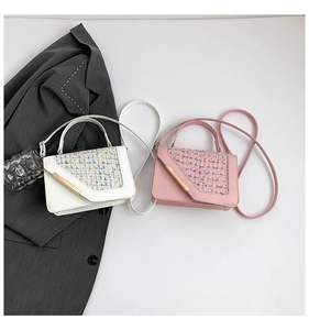 Detail view of tweed patchwork shoulder bag with metallic gold bar and leather strap