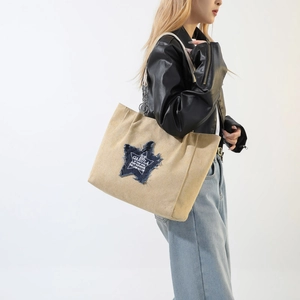 Chic khaki canvas tote bag featuring a denim star patch and decorative metal chain strap