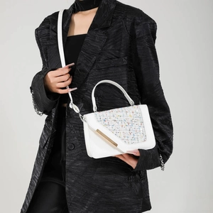 White tweed square crossbody bag with gold buckle and elegant handle on a model