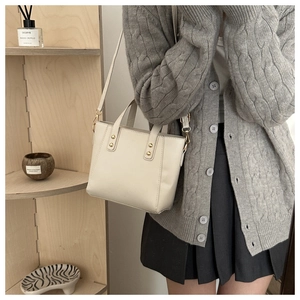Détail du sac fourre-tout minimaliste blanc cassé avec rivets dorés et bandoulière