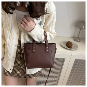 Détail d'un sac en cuir marron avec rivets dorés et bandoulière réglable en décor de vie