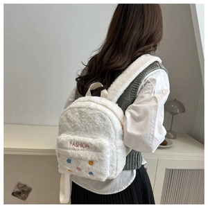 Detail of white plush backpack featuring pink FASHION embroidery and colorful dots