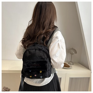 Detail of black plush backpack featuring colorful buttons and red Fashion embroidery