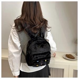 Detail of black faux fur backpack featuring colorful button eyes and soft plush texture