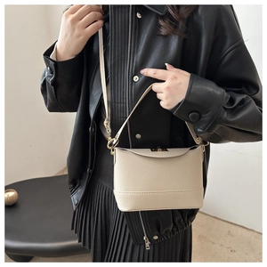 Detail of cream lychee-grain leather bucket bag with gold clasp and shoulder strap