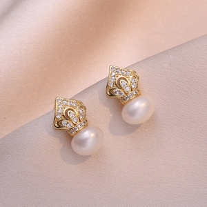 Golden crown stud earrings with sparkling zircons and white freshwater pearls on silk