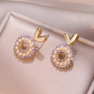 Elegante goldene Herzohrringe mit lila Zirkonia und Perlen in einer Samt-Schmuckschatulle