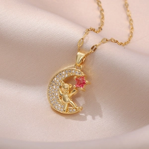Collier lune dorée avec pendentif ours en zircon et étoile rose sur fond de soie