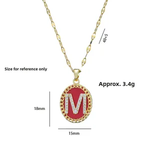 Detail of gold M-letter pendant with red enamel and pavé crystals, 18x15mm size