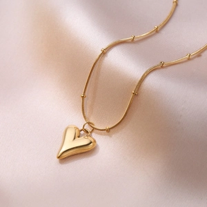 Collier minimaliste avec pendentif cœur doré et chaîne perlée sur fond de soie douce