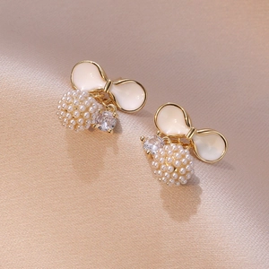 Elegant bow earrings with pearl clusters and zircon stones on a champagne silk fabric
