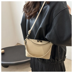 Detail of beige lychee leather crossbody bucket bag with elegant gold metal twist lock