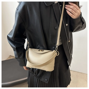 Close-up of light beige lychee pattern leather handbag with gold metal twist lock detail
