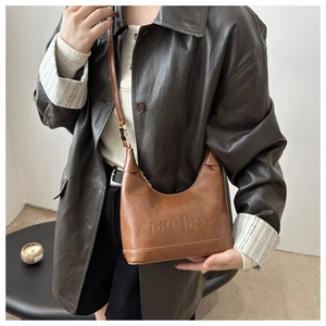 Detail of matte brown faux leather hobo bag featuring embossed gaoihse letter branding