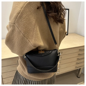 Close-up of black lychee texture leather shoulder bag with golden metallic swivel clasp