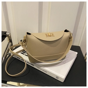 Detail of lychee pattern leather crossbody bag with golden twist lock on a white book