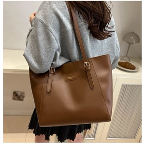 Brown leather large tote bag with adjustable straps shown on model for daily commuting