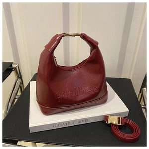 Detail of burgundy dumpling bag showing golden metal buckle and embossed lettering
