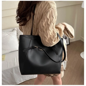 Large black faux leather tote bag with decorative straps for commuting and casual wear