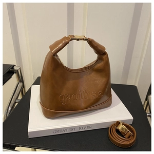 Detail of dark brown leather half-moon bag with embossed text and gold hardware accents