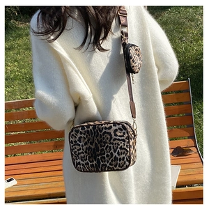 Outdoor shot of a leopard print crossbody bag with a round coin purse on a wide strap