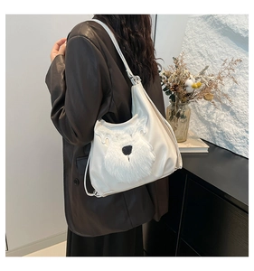 Detail of white faux leather tote featuring a plush schnauzer design worn as a crossbody bag