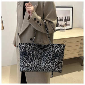 Close-up of leopard print tote bag styled with a beige coat in a warm interior setting