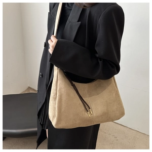 Detail of khaki suede hobo bag with decorative side string and metallic tip on shoulder
