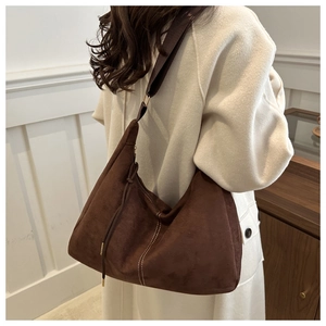 Detail of dark brown suede hobo bag with white stitching and adjustable strap