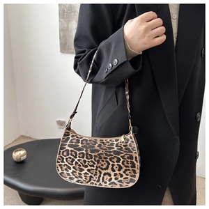 Detail of leopard print baguette bag with golden zipper on a black blazer model outfit