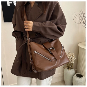 Détail d'un sac à bandoulière vintage en cuir marron mat avec boucles et zips argentés
