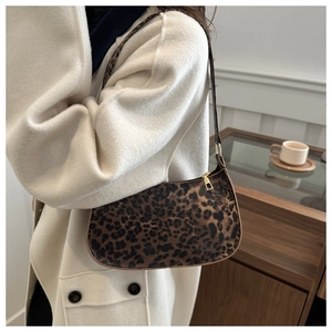 Detail shot of leopard print baguette bag on model wearing a cream wool coat