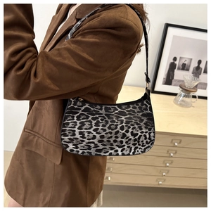Close-up of leopard print baguette bag with black faux leather trim and shoulder strap
