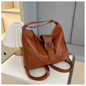 Détail d'un sac à dos vintage en cuir marron avec boucle et poches zippées en diagonale
