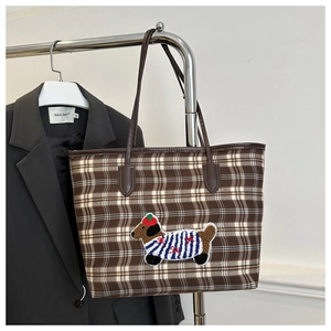 Détail de la broderie de chien sur un sac cabas à carreaux marron avec bordure en cuir
