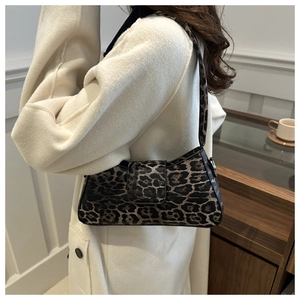 Close-up of a trendy leopard print underarm bag worn by a model in a white coat
